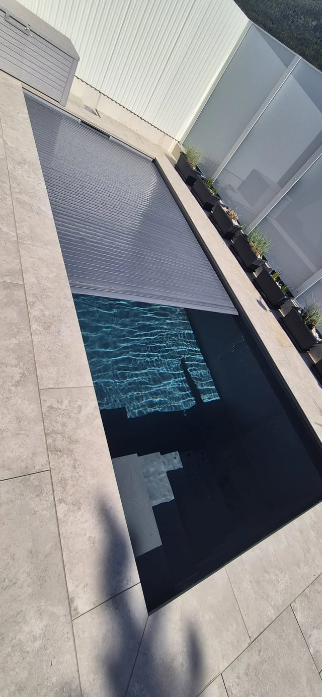 Pool mit teilweise geschlossener Lamellenabdeckung.
