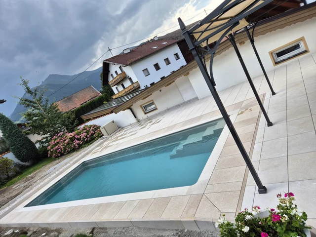 Ein Pool, eingebettet in Terrasse und Garten.