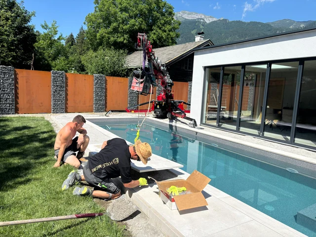 Das Team verlegt die Umrandung am Pool.